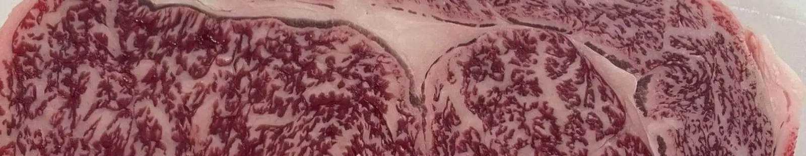 Anschnitt eines Fullblood-Wagyu-Steaks aus der Nähe: dichte Fettadern durchziehen den Muskel, das Fettauge sitzt am Rand
